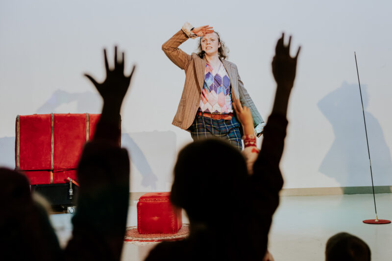 Aktor na scenie, widać dzieci podnoszące ręce